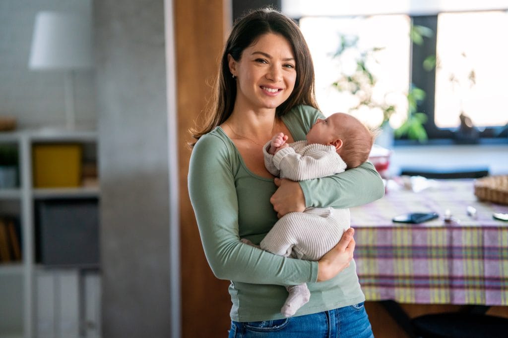 Loving single mother carrying of her newborn baby at home. People love care family concept