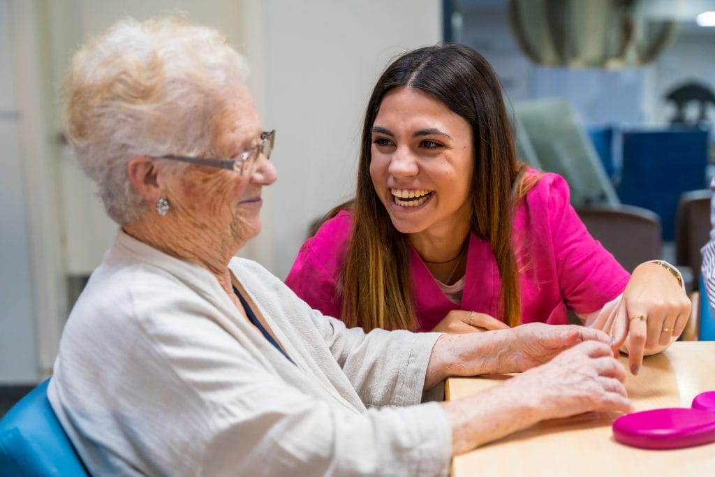 Woman and nurse playing board game in a nursing home
